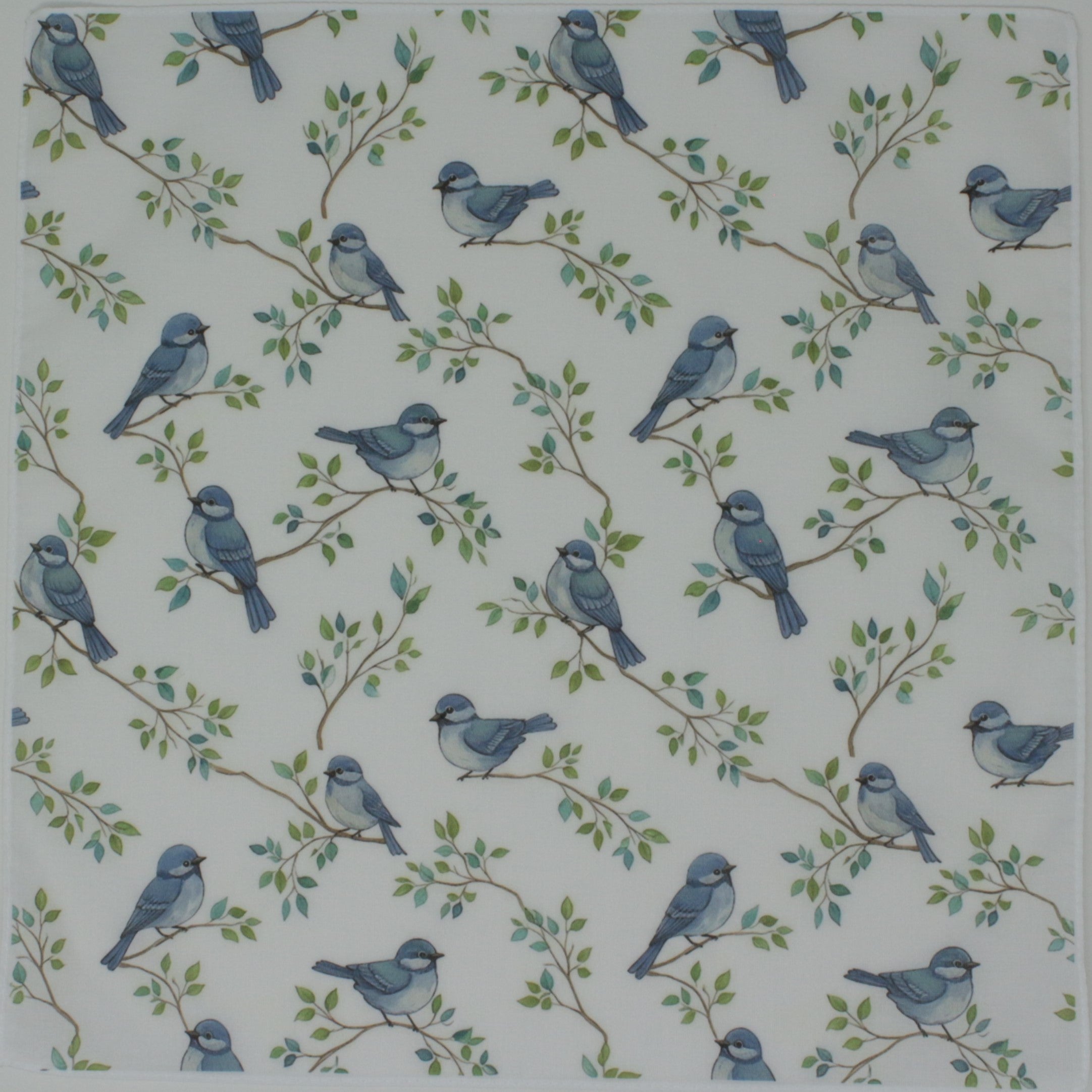 A square fabric cotton handkerchief featuring a repeating pattern of small blue birds perched on delicate green leafy branches over an off-white background.