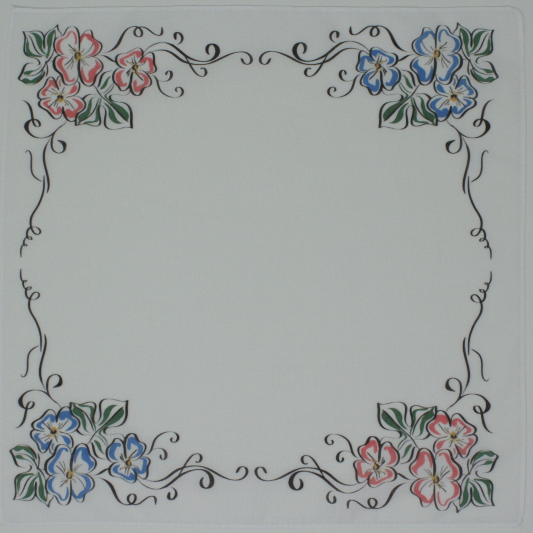 A square white cotton handkierchief, decorative floral border design in the corners, with pink and blue flowers, green leaves, and black scrollwork.