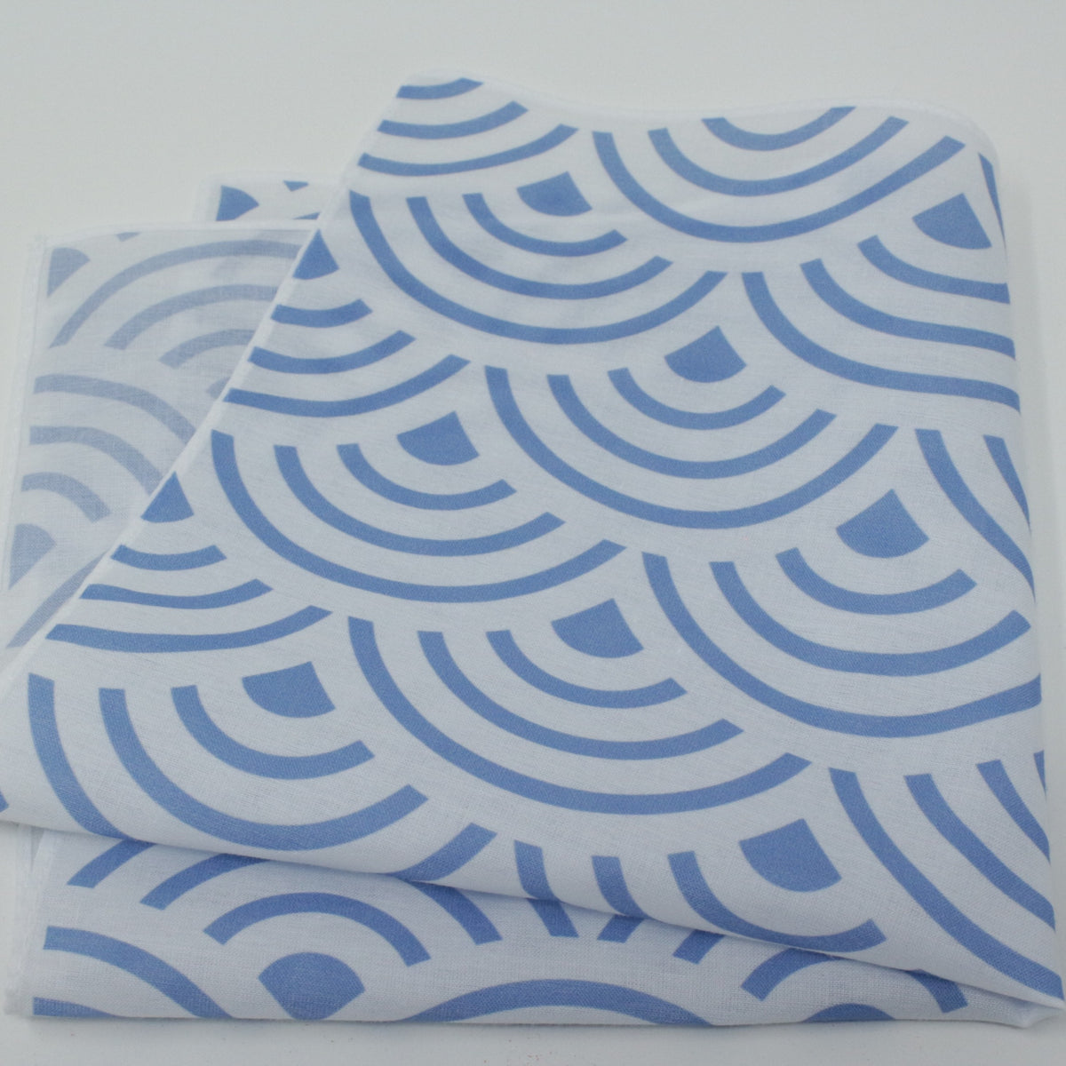 A folded cotton handkerchief pocket square, featuring a repeating blue scallop or wave-like geometric pattern. Japanese