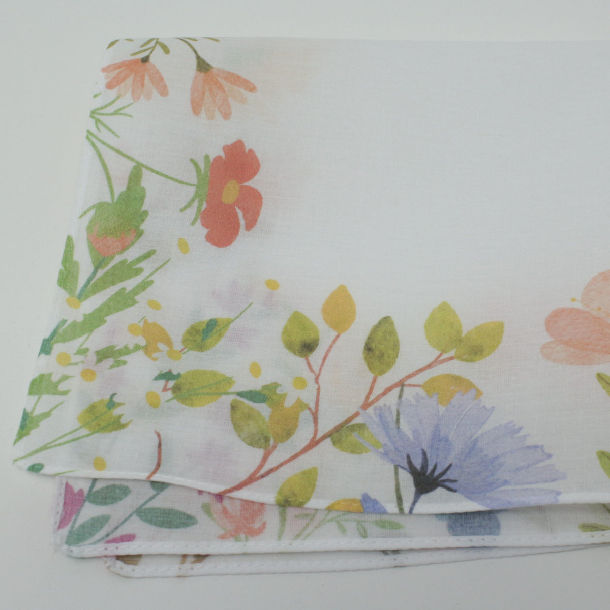 A folded white Meadow Flowers Border featuring a delicate watercolor-style floral print with green leaves, pink and orange blossoms, and a light blue flower.